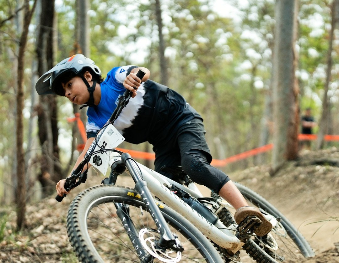 Young rider leaning hard into a corner during a Bike On mountain bike lesson