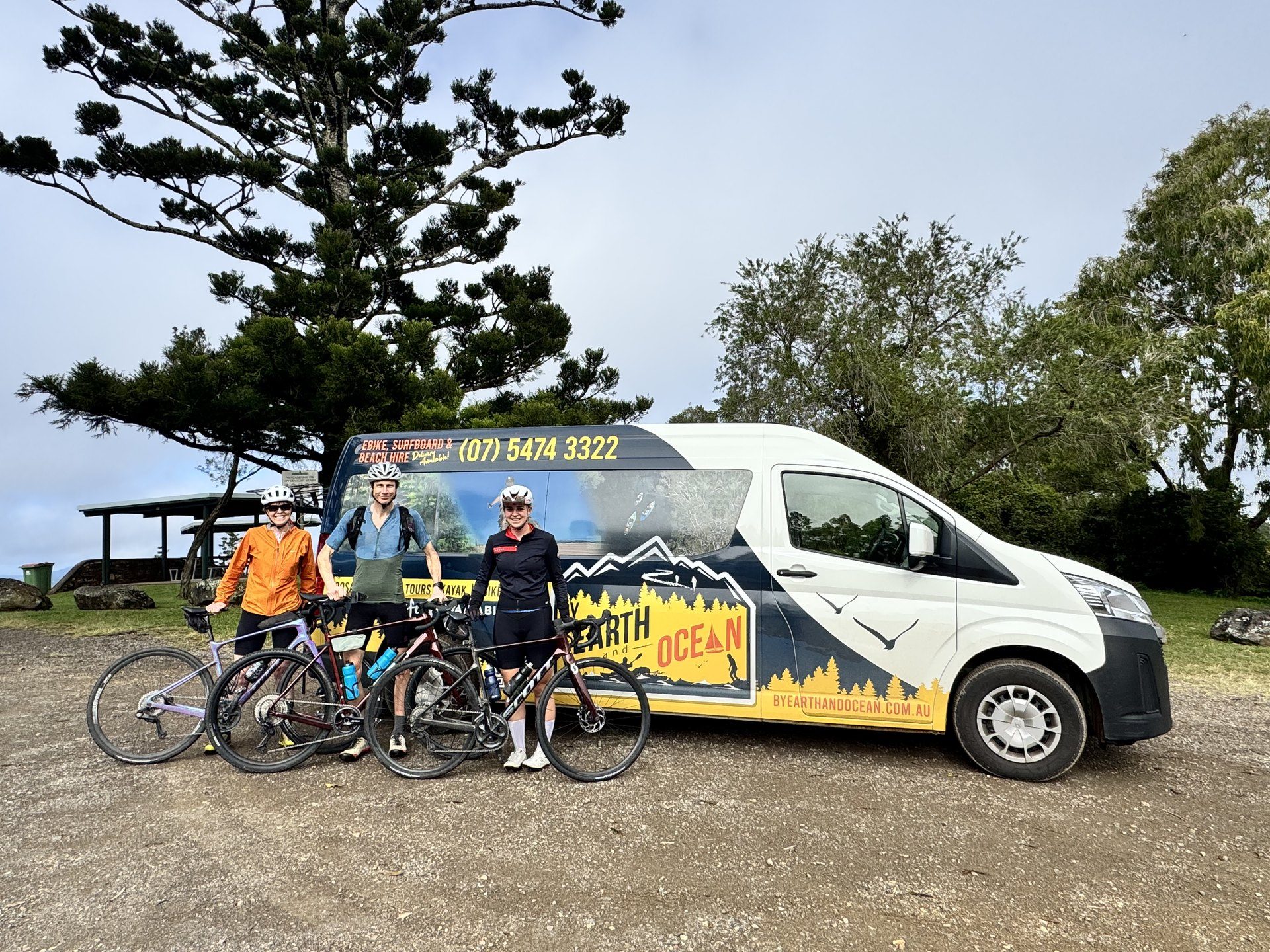 Three riders with their bikes beside the By Earth and Ocean bus