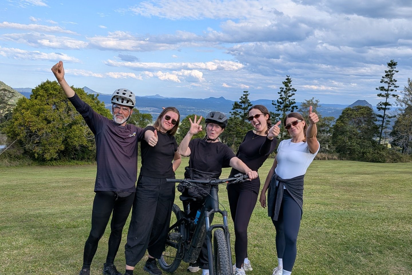 Guide and riders cheering at a hinterland lookout on a guided mountain bike tour