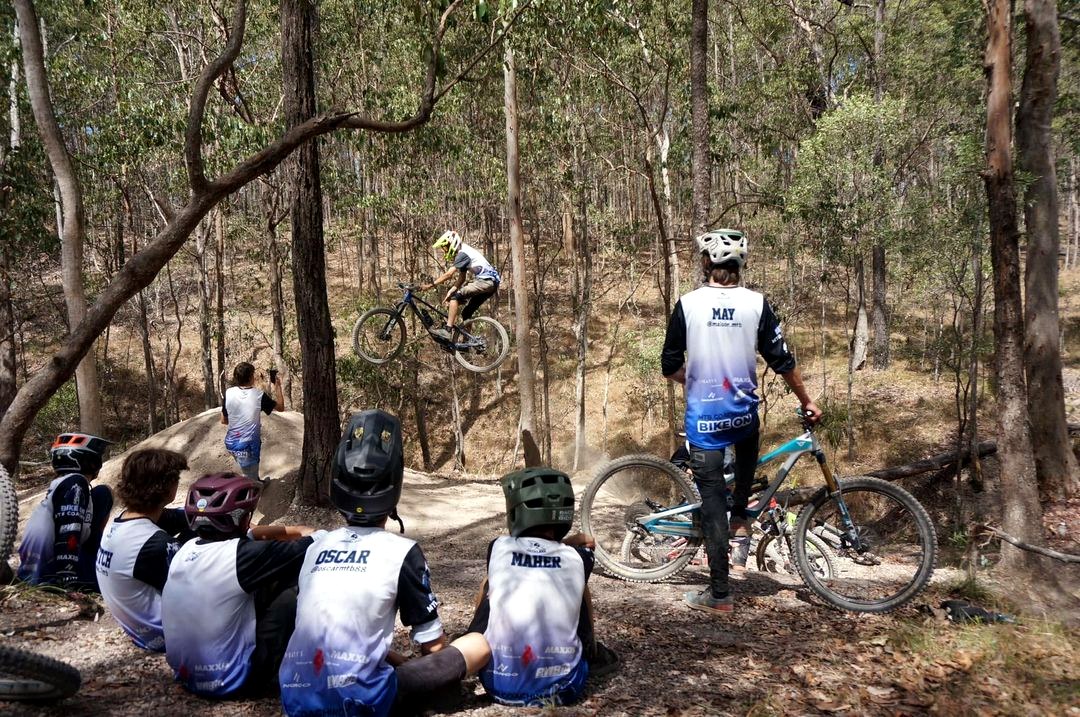 Bike On riders and coach watching a teammate jump during a coaching session
