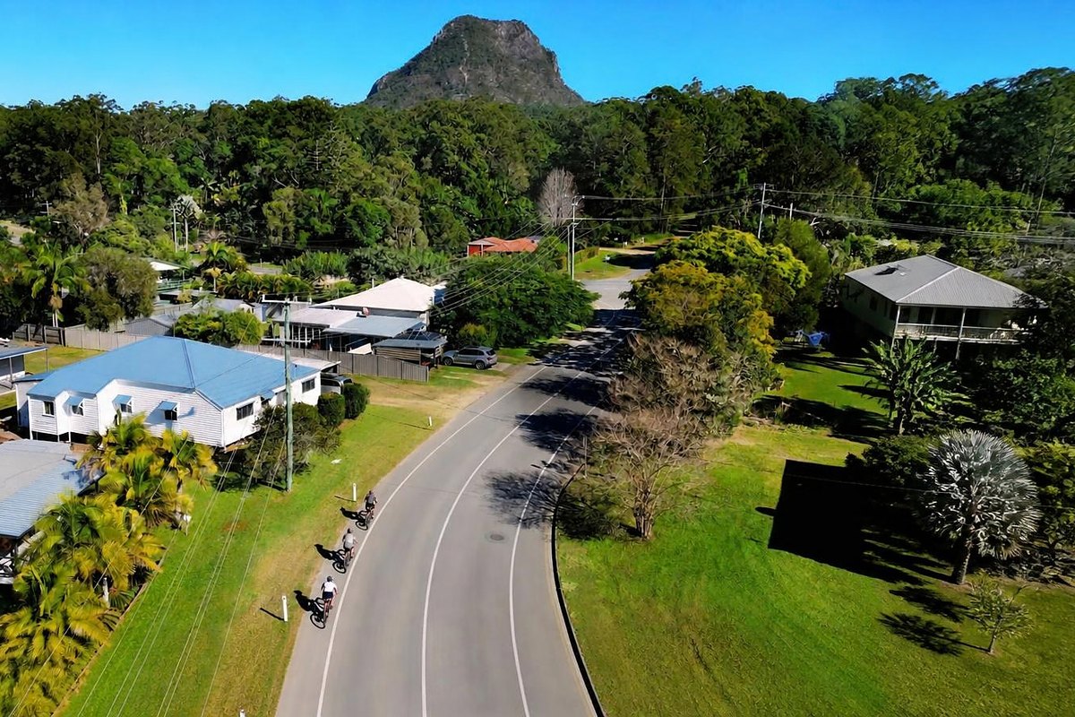 Road cyclists riding into Pomona with Mt Cooroora behind
